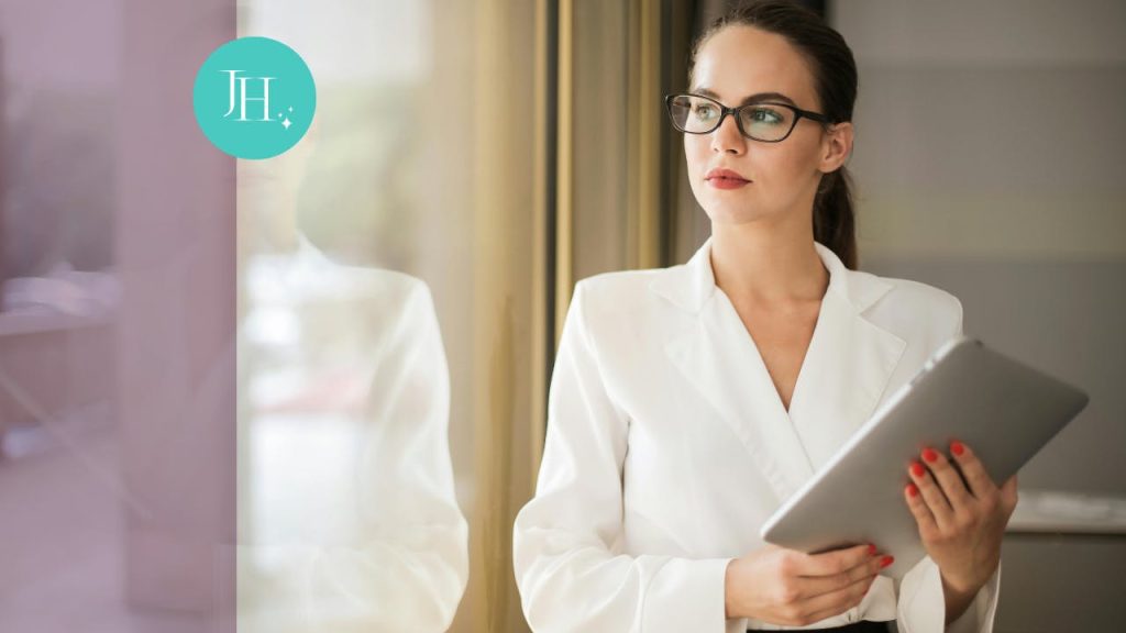 a woman in a white suit, looking out a large office window - A reality check for self-care for preventing burnout