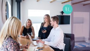 Group of 4 people gathered around a conference table having a discussion.